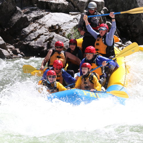 Group on a rafting adventure hitting water that splashes all around