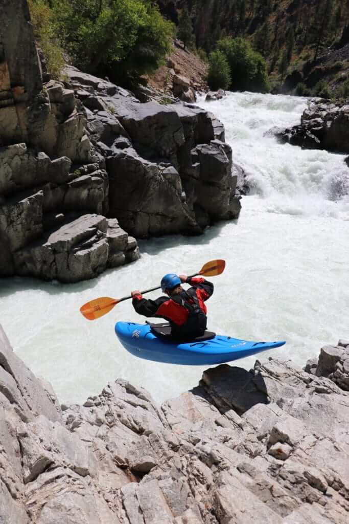 Man in canoe flying over rocks